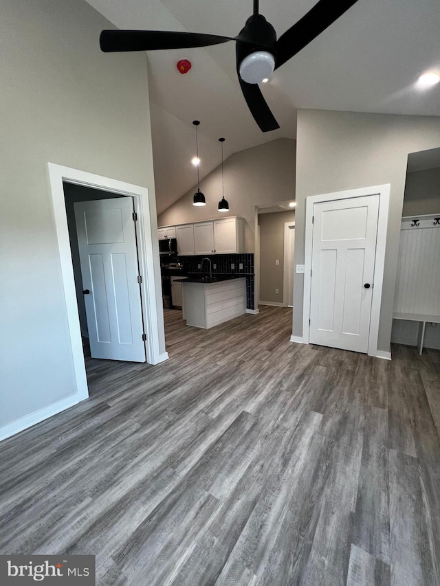 unfurnished living room featuring high vaulted ceiling, sink, hardwood / wood-style flooring, and ceiling fan