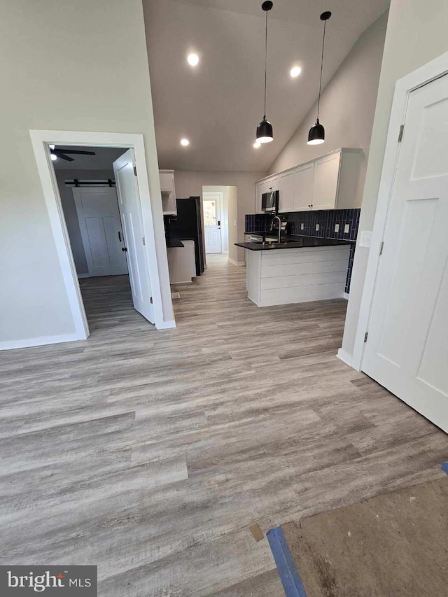 kitchen with light wood-type flooring, hanging light fixtures, sink, and white cabinets