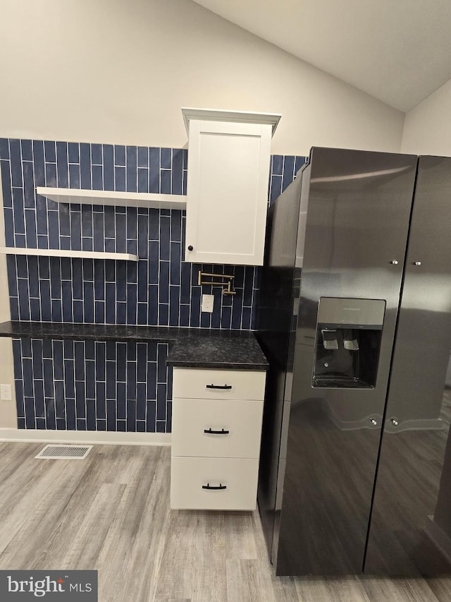 kitchen featuring white cabinetry, lofted ceiling, stainless steel fridge with ice dispenser, and light wood-type flooring