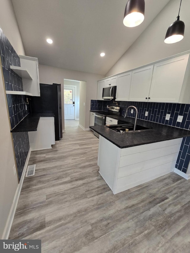 kitchen featuring white cabinetry, appliances with stainless steel finishes, light wood-type flooring, lofted ceiling, and pendant lighting