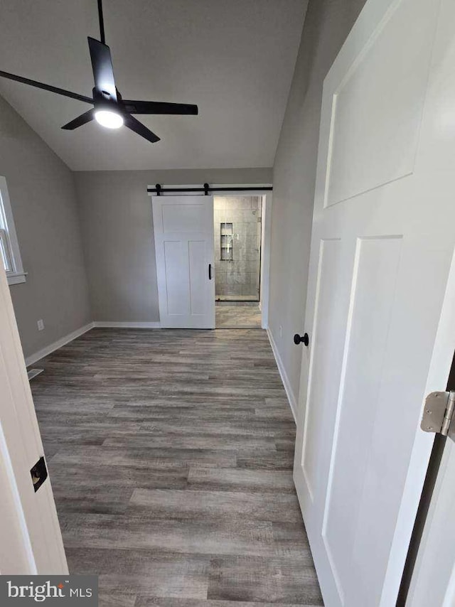 spare room featuring a barn door, wood-type flooring, and ceiling fan