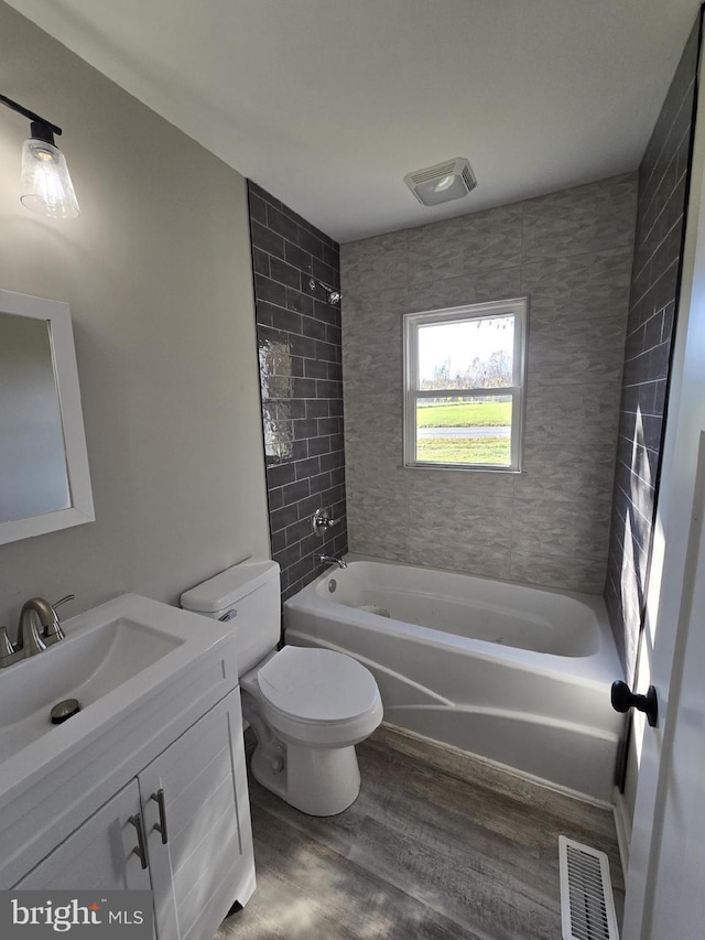 full bathroom with wood-type flooring, toilet, vanity, and tiled shower / bath