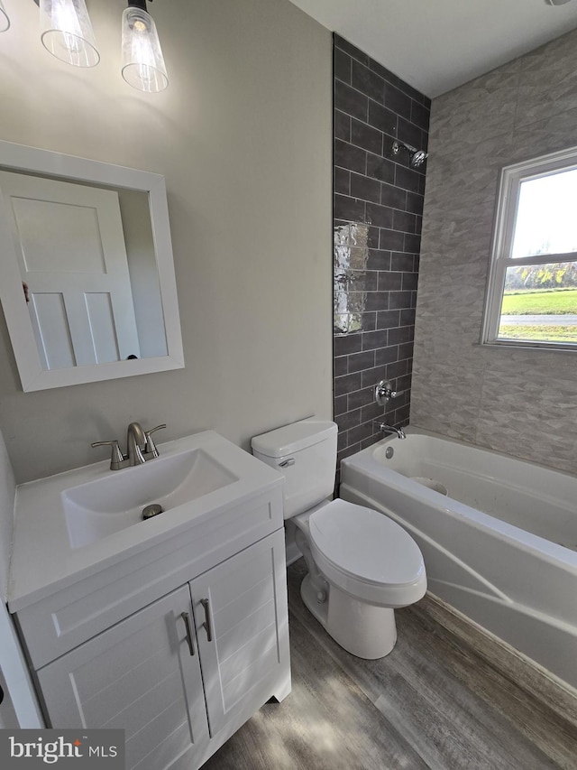 full bathroom featuring wood-type flooring, tiled shower / bath combo, toilet, and vanity