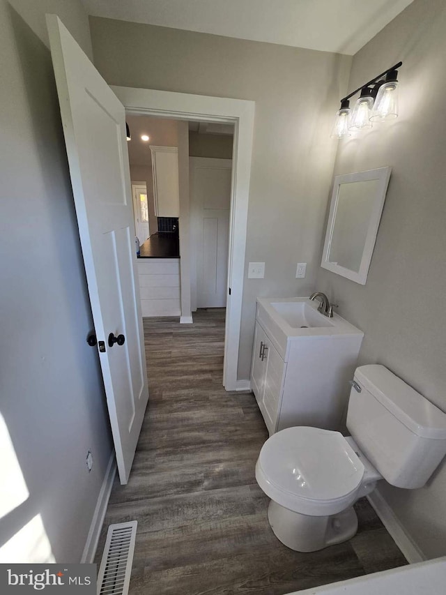 bathroom with wood-type flooring, vanity, and toilet