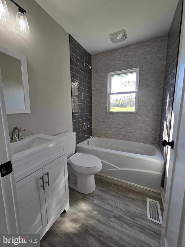 full bathroom featuring wood-type flooring, vanity, toilet, and tiled shower / bath combo