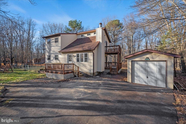 exterior space featuring a garage, an outbuilding, and a deck