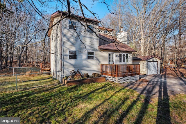 rear view of house with an outdoor structure, a wooden deck, and a yard