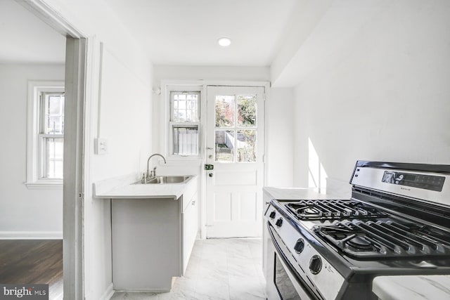 kitchen featuring light wood-type flooring, gas range, and sink