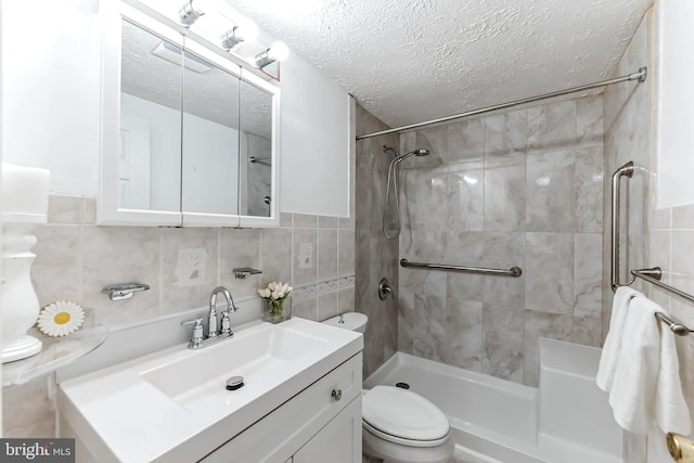 bathroom featuring tile walls, a tile shower, vanity, a textured ceiling, and toilet