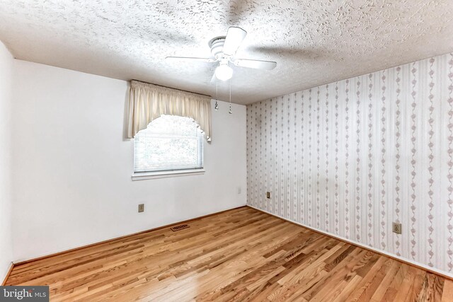 spare room featuring hardwood / wood-style floors, ceiling fan, and a textured ceiling