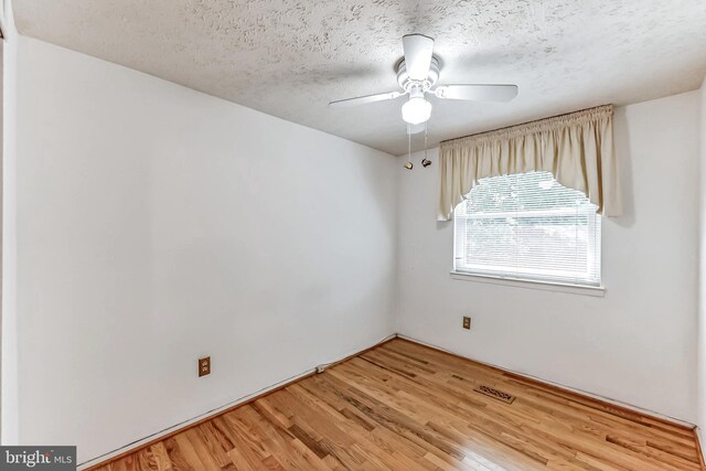 empty room with a textured ceiling, ceiling fan, and light hardwood / wood-style flooring