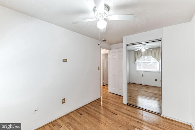 unfurnished bedroom featuring a closet, a textured ceiling, hardwood / wood-style flooring, and ceiling fan