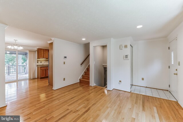 unfurnished living room with a chandelier and light hardwood / wood-style flooring