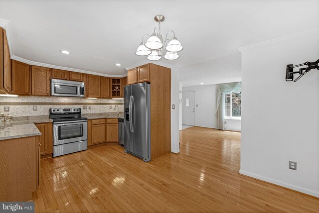 kitchen featuring light wood-type flooring, appliances with stainless steel finishes, a notable chandelier, hanging light fixtures, and sink