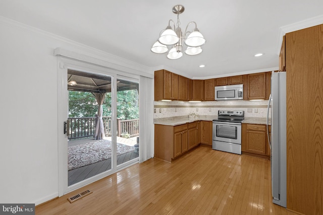 kitchen with an inviting chandelier, light hardwood / wood-style flooring, hanging light fixtures, crown molding, and appliances with stainless steel finishes