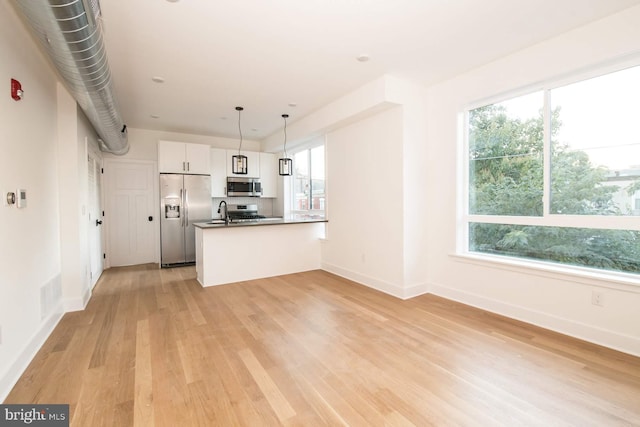 kitchen with white cabinetry, stainless steel appliances, a healthy amount of sunlight, and decorative light fixtures