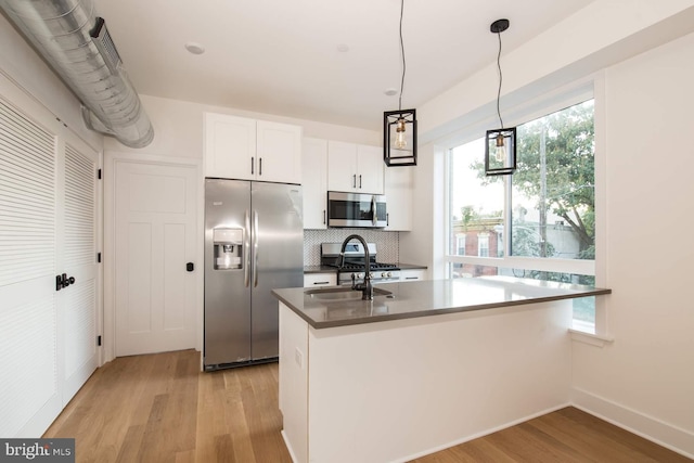 kitchen with pendant lighting, white cabinets, light hardwood / wood-style floors, and stainless steel appliances