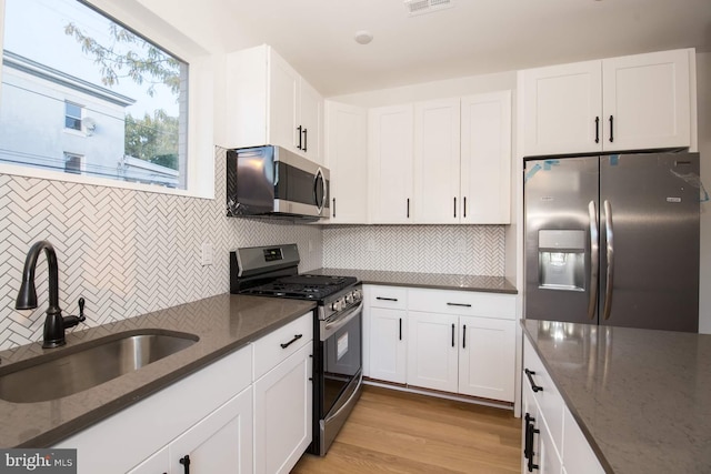 kitchen featuring dark stone countertops, white cabinetry, appliances with stainless steel finishes, and sink