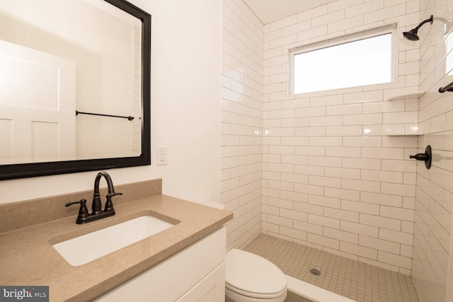 bathroom featuring tiled shower, toilet, and vanity