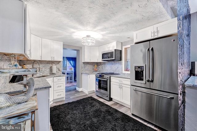 kitchen featuring light hardwood / wood-style floors, light stone countertops, white cabinetry, and stainless steel appliances