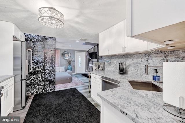 kitchen with white cabinetry, stainless steel appliances, and light wood-type flooring