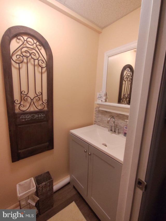 bathroom with backsplash, hardwood / wood-style floors, vanity, and a textured ceiling