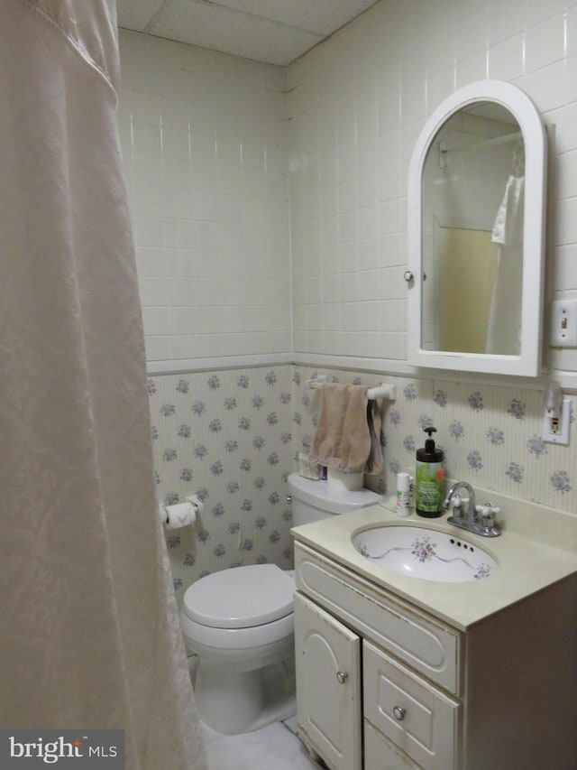 bathroom with a paneled ceiling, vanity, and toilet