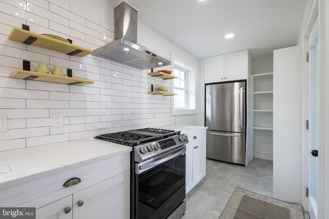 kitchen with light stone countertops, stainless steel appliances, white cabinets, and range hood