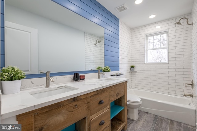 full bathroom with vanity, hardwood / wood-style flooring, toilet, and tiled shower / bath