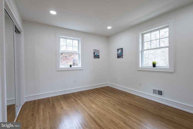 unfurnished bedroom featuring multiple windows, a closet, and light wood-type flooring