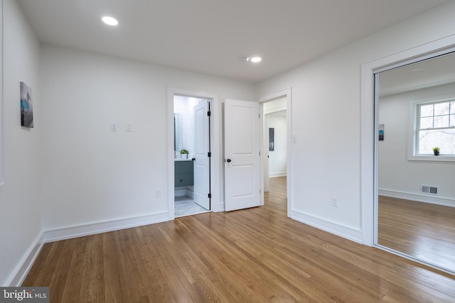 unfurnished bedroom featuring light hardwood / wood-style floors, a closet, and ensuite bathroom