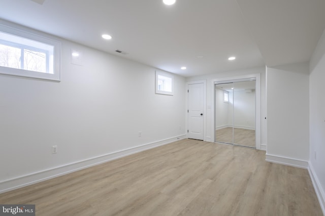 basement with light hardwood / wood-style floors and a wealth of natural light