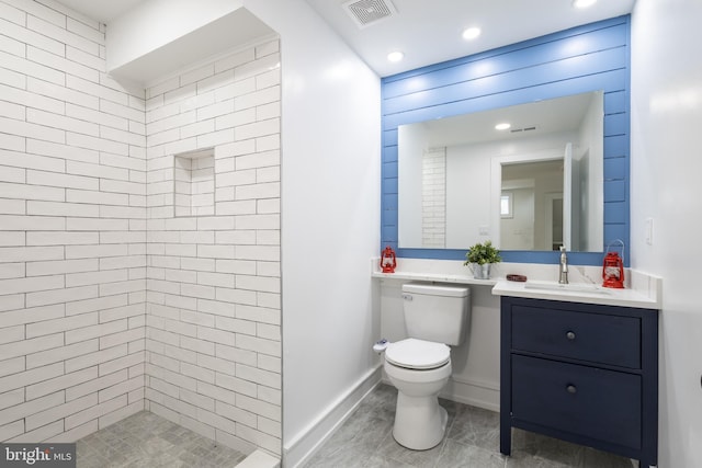 bathroom with vanity, toilet, and a tile shower