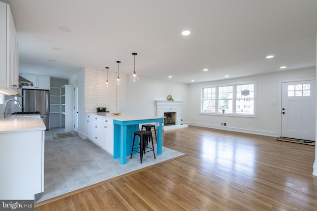 kitchen featuring a center island, white cabinets, a kitchen breakfast bar, light hardwood / wood-style flooring, and decorative light fixtures