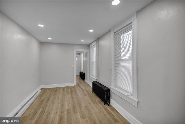 unfurnished living room featuring radiator heating unit and light hardwood / wood-style flooring