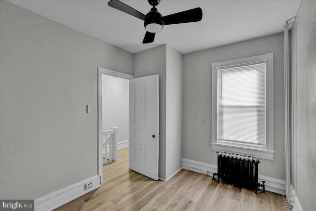 bedroom featuring ceiling fan, radiator heating unit, and light hardwood / wood-style flooring