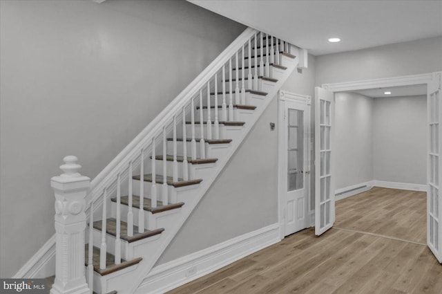 stairs with hardwood / wood-style floors, french doors, and a baseboard heating unit