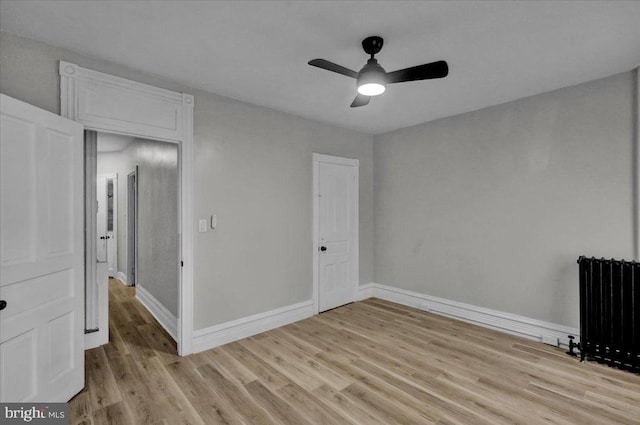 unfurnished bedroom with light hardwood / wood-style floors, radiator, and ceiling fan