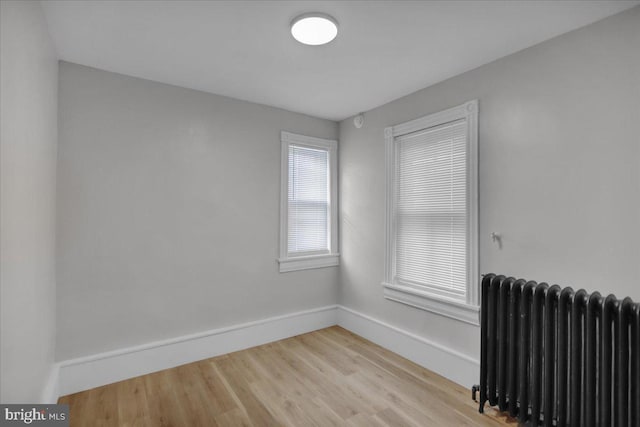 empty room with light hardwood / wood-style flooring and radiator