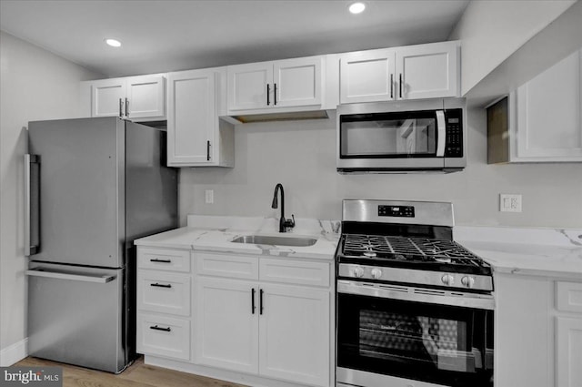 kitchen with appliances with stainless steel finishes, white cabinetry, and sink