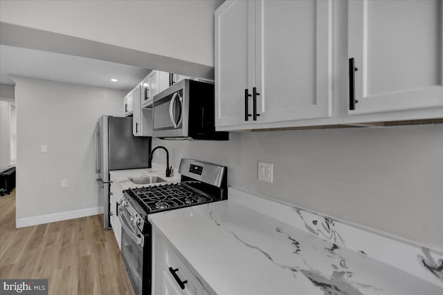 kitchen with white cabinetry, sink, stainless steel appliances, and light hardwood / wood-style floors