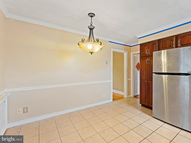 kitchen with stainless steel refrigerator, light tile patterned floors, decorative light fixtures, and crown molding