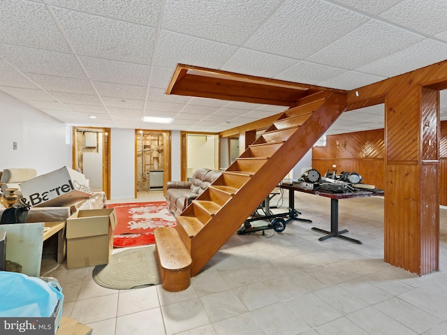 interior space featuring tile patterned flooring, wooden walls, and a paneled ceiling