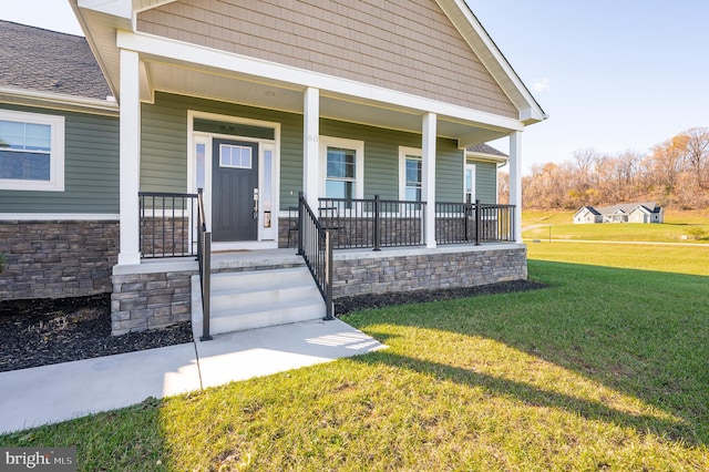 entrance to property featuring covered porch and a yard