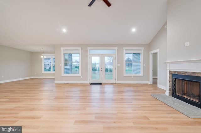 unfurnished living room featuring ceiling fan, french doors, high vaulted ceiling, and light wood-type flooring