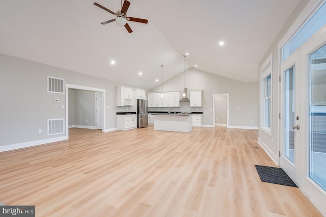 unfurnished living room with ceiling fan, lofted ceiling, sink, and light hardwood / wood-style flooring