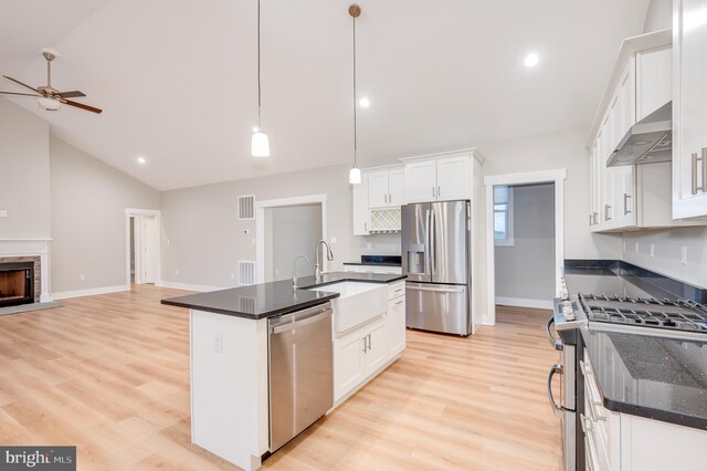 kitchen with extractor fan, vaulted ceiling, decorative light fixtures, white cabinets, and appliances with stainless steel finishes