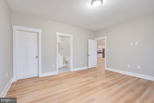 unfurnished bedroom featuring connected bathroom and light hardwood / wood-style floors