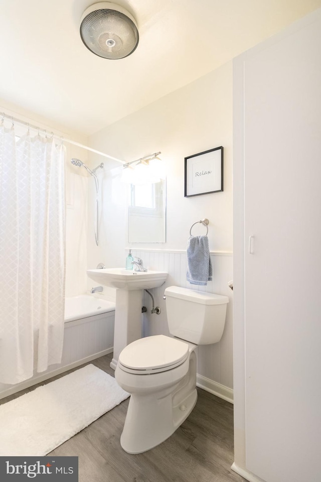 bathroom featuring hardwood / wood-style floors, toilet, and shower / bath combo with shower curtain