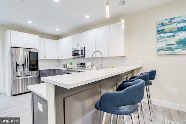 kitchen featuring white cabinetry, kitchen peninsula, appliances with stainless steel finishes, and a kitchen bar